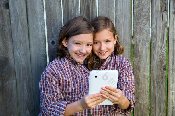 双胞胎女孩装扮成暹罗人和平板电脑