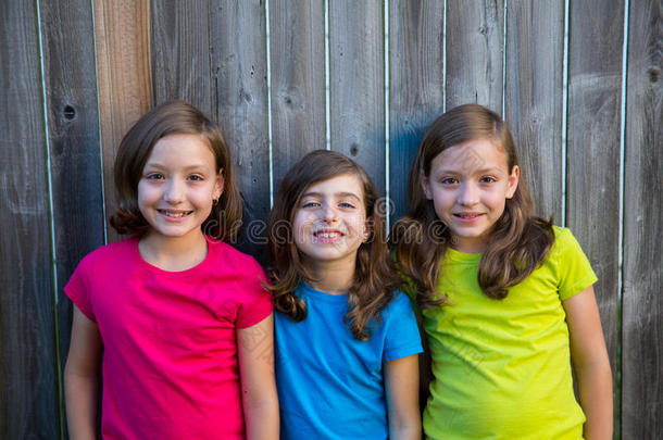 《姐妹和朋友》小女孩们在灰色篱笆上微笑的画像