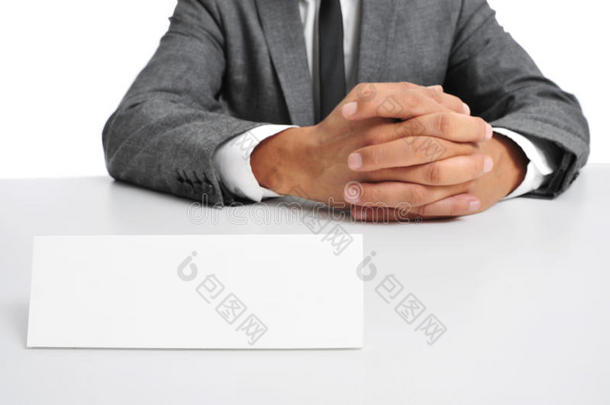 西装革履的男人坐在桌子上，前面有一块空白的招牌