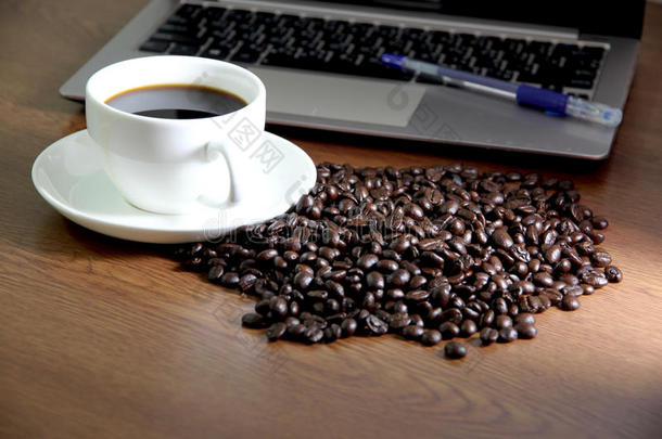 咖啡在电脑笔记本旁边的白色杯子里。