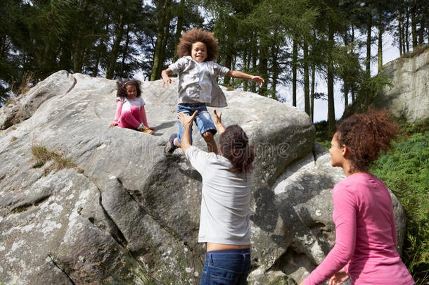 <strong>父亲帮助</strong>孩子们从岩石上跳下来