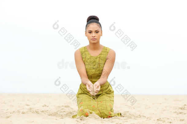 坐在沙滩上手上<strong>流沙</strong>的美丽年轻女子