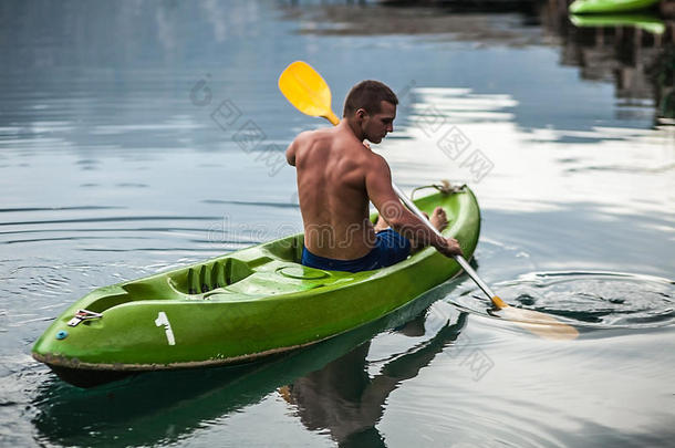 在泰国风景如画的湖面上划独木舟的强壮的年轻人。