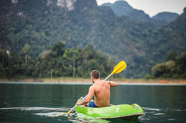 在泰国风景如画的湖面上划独木舟的强壮的年轻人。