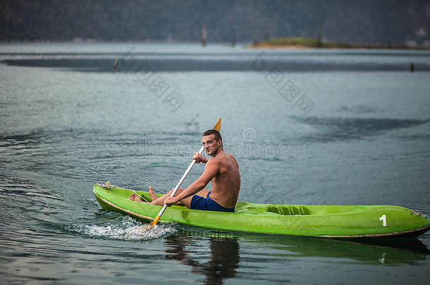 在<strong>泰国风</strong>景如画的湖面上划独木舟的强壮的年轻人。
