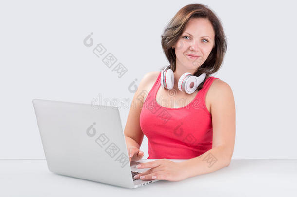 年轻女子正坐在带蓝牙耳机的笔记本电脑前