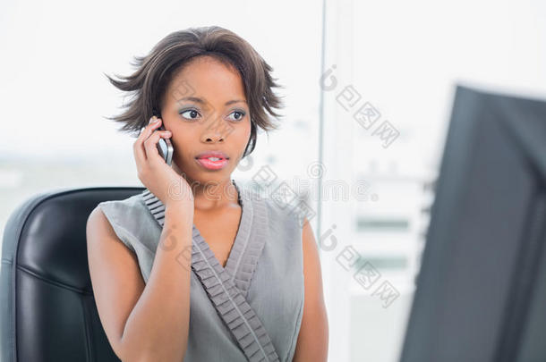 严肃的女人一边打电话一边看着电脑屏幕