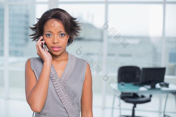 严肃的女商人站在办公室里打电话