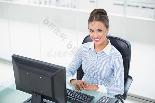 坐在办公桌旁微笑的黑发女商人