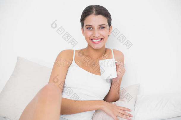 穿着白色睡衣、兴高采烈的棕色头发的年轻模特正在享受咖啡