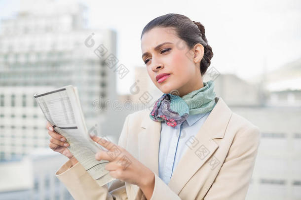 专心致志的棕色头发的女商人在看报纸