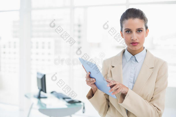 严肃聪明的棕色头发女商人拿着平板电脑