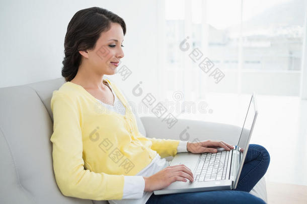 迷人的浅棕色休闲装，黄色开襟<strong>羊毛</strong>衫，在笔记本电脑上打字