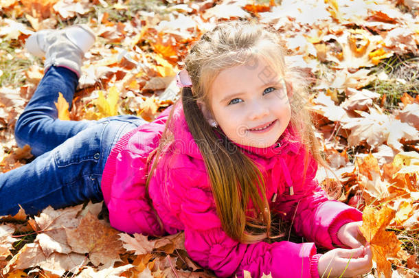 可爱的小女孩躺在枫叶上的秋画像