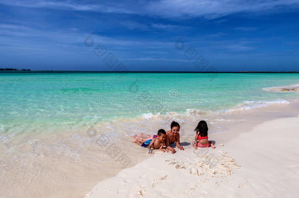 母亲和她的孩子们在可可岛白色的古巴沙滩上玩耍