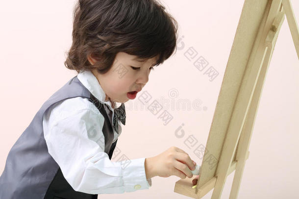 小黑发男孩在黑板上用粉笔画