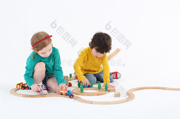 小可爱的女孩和男孩在木制铁路上滚动火车