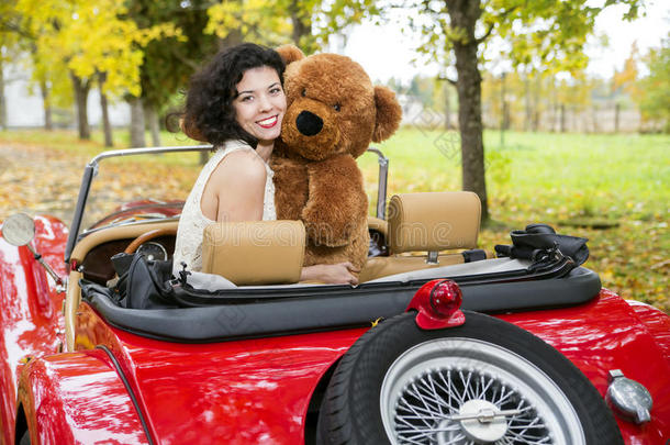 怀旧车上带熊玩具的女人