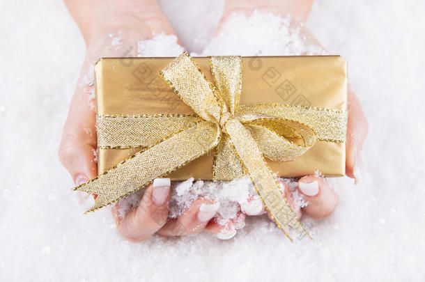 一位女士手里拿着一份金色圣诞礼物-指甲护理优惠券