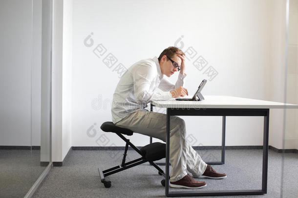 年轻人对他的平板电脑。坏工作时的坐姿