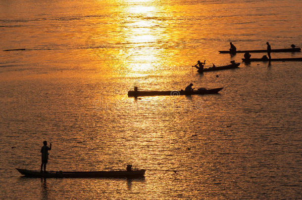 许多渔夫划着小船在日落时钓鱼，剪影