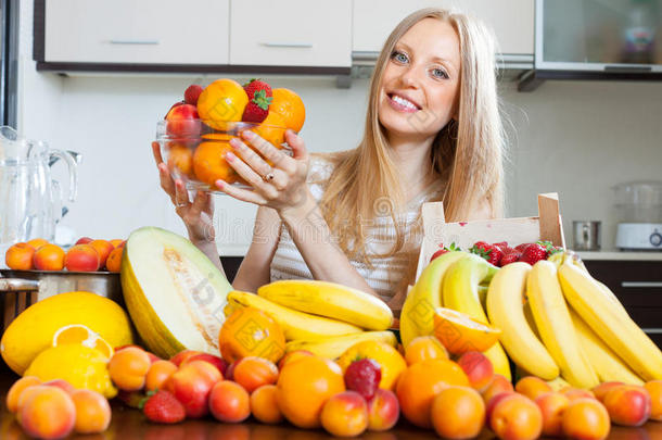 一个快乐的金发女人，带着一堆各式各样的水果