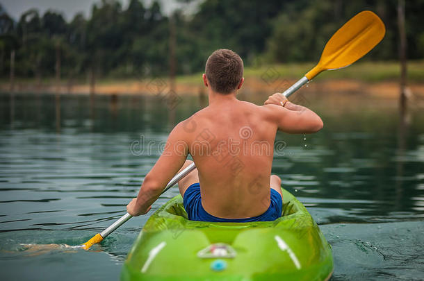 在<strong>泰国风</strong>景如画的湖面上划独木舟的强壮的年轻人。