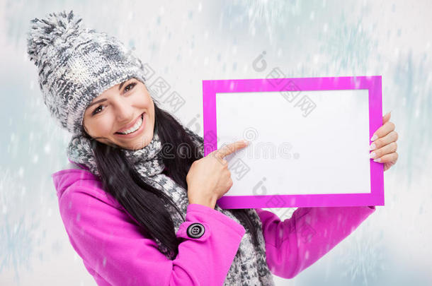 微笑的女孩指着一块空白的木板，围着雪转