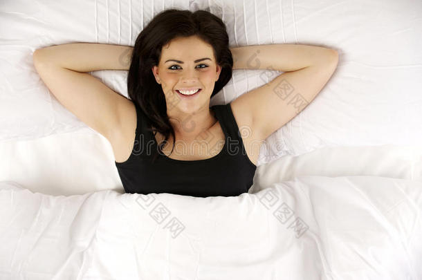 躺在床上的女人轻松地抬头看着镜头微笑着