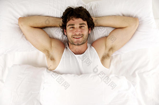 躺在白色床上的男人<strong>抬头</strong>看着镜头微笑着
