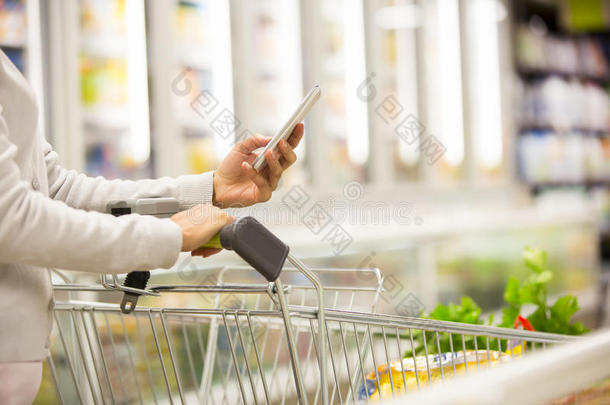 妇女在超市购物时使用手机