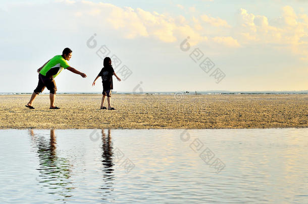 一位父亲和女儿沿着海滩跑步