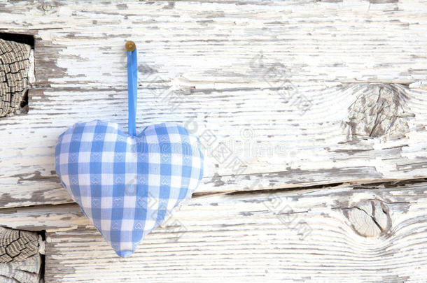 浪漫的蓝/白格子心形挂在白色木质表面的钉子上-白色木质破旧别致的背景