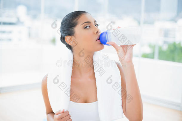 平静色调的黑发女人，用运动瓶里的毛巾喝水