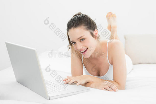 在床上用笔记本电脑微笑的休闲女人