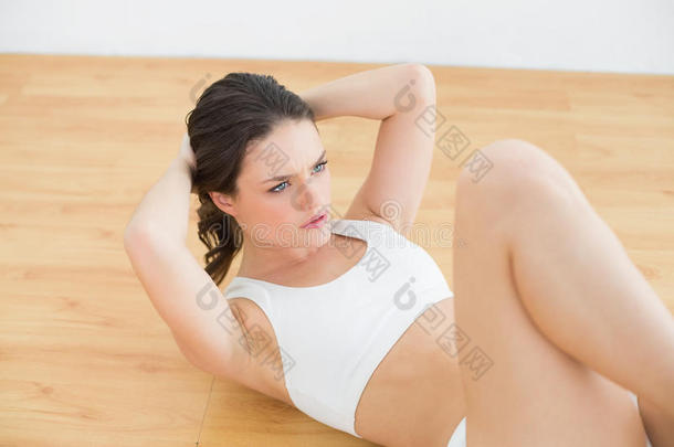 运动型健身女青年在健身室做仰卧起坐