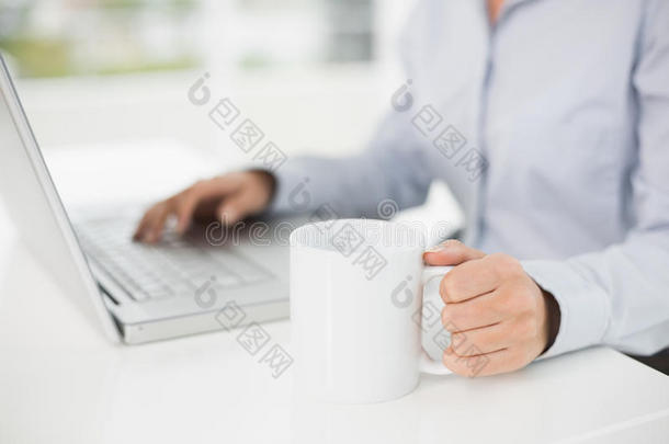 女商人一边喝咖啡一边用笔记本电脑的中间部分
