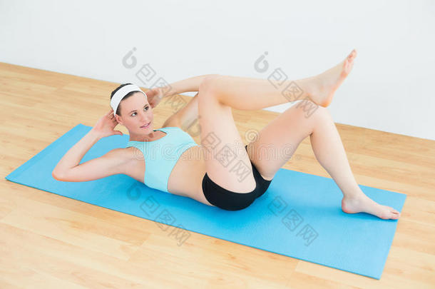 运动<strong>型身材</strong>的女人在运动垫上做仰卧起坐