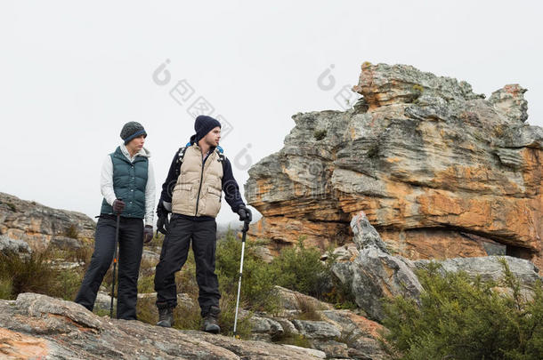 一对在岩石景观上的夫妇，在天空中用<strong>登山杖</strong>行走
