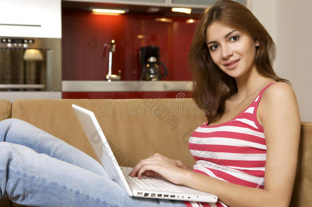 一位年轻女子躺在<strong>白色沙发</strong>上，手里拿着一台笔记本电脑。