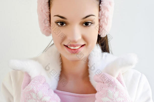 戴着粉色耳罩和带着雪花的可爱手套微笑的漂亮女孩。
