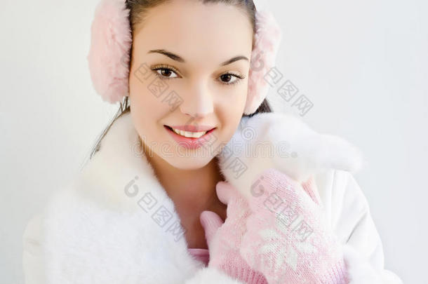 戴着粉色耳罩和带着雪花的可爱手套微笑的漂亮女孩。