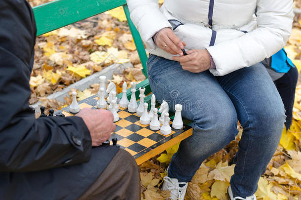 老人和女人在公园的木凳上围棋