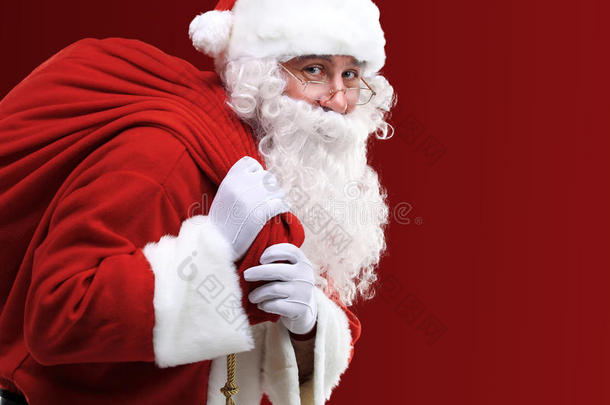 圣诞老人提着一个红色的大袋子，里面装着礼物
