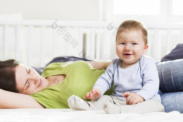 和妈妈一起坐在床上笑的小男孩。