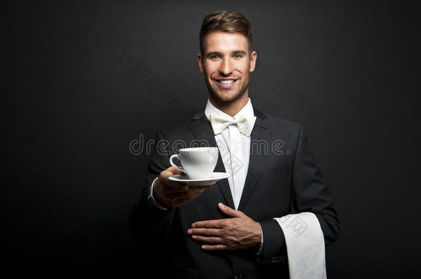 穿制服的年轻服务员，<strong>端着</strong>热咖啡