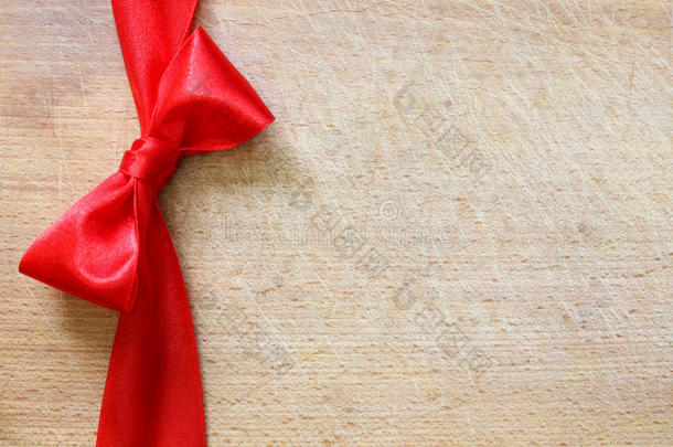 红色丝带和蝴蝶结在复古的圣诞剪纸背景上