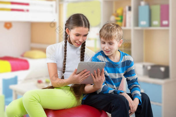 女孩和男孩看着一个垫平板电脑屏幕