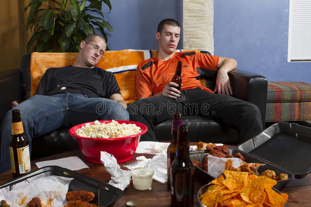 两个疲惫的男人在电视上看了体育比赛后