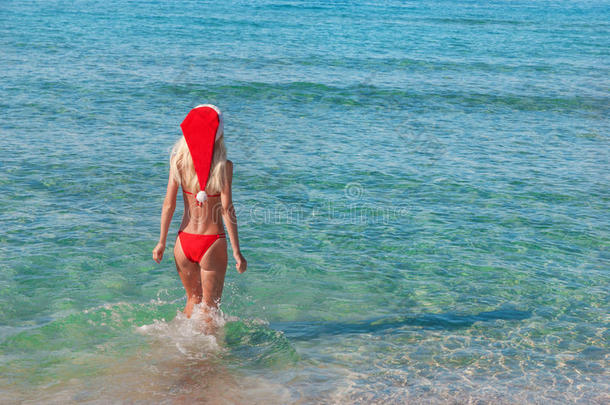 美丽的金发女人戴着<strong>红色</strong>圣诞帽在<strong>海边</strong>。